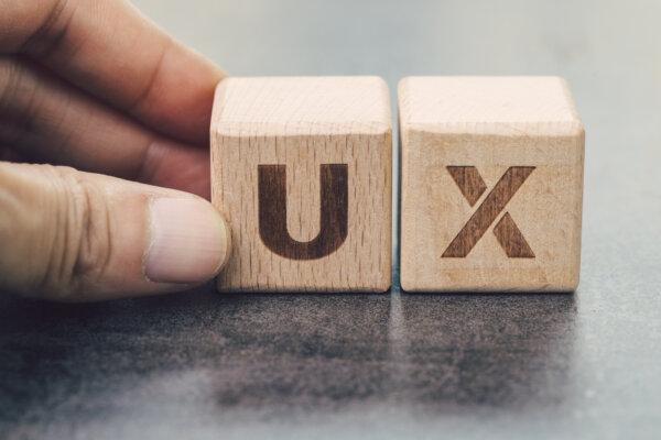 UX development, User Experience design concept, hand building cube wooden block with alphabet U and X on blackboard, user centric in modern world business, product and service design